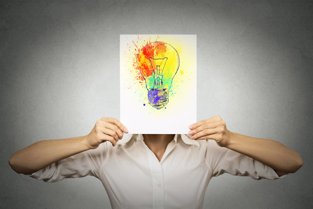 woman having brilliant idea colorful lightbulb covering face isolated grey wall background. Free thinking, new approach, alternative technology. Creativity, imagination, dynamism, intelligence concept