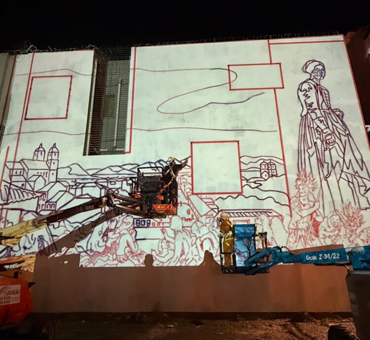 Projeção do mural “Anunciação” na empena do Museu Victor Meirelles, na noite de segunda-feira (17/08), dando início à pintura que abre a terceira edição do Street Art Tour. A obra, de Bernardo Dartagnan e Henrique Doss, revisita o legado do pintor catarinense Victor Meirelles. Foto Bárbara Branco